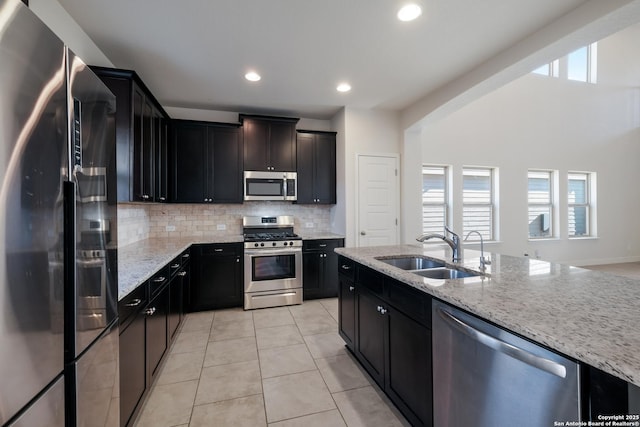 kitchen with light stone counters, sink, light tile patterned flooring, and appliances with stainless steel finishes