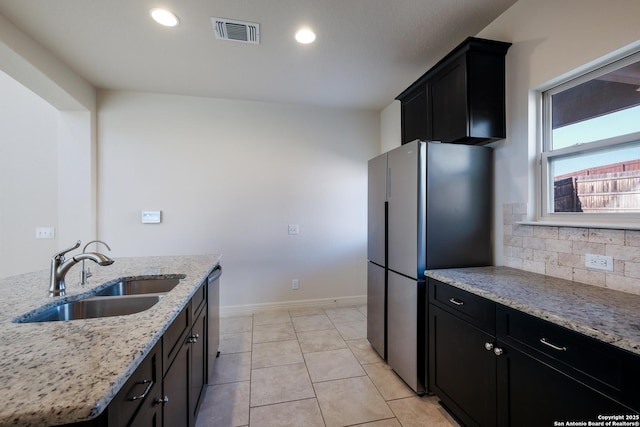 kitchen featuring light stone counters, sink, decorative backsplash, and appliances with stainless steel finishes