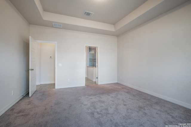 empty room featuring light colored carpet and a tray ceiling