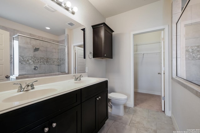 bathroom featuring tile patterned flooring, vanity, toilet, and a tile shower