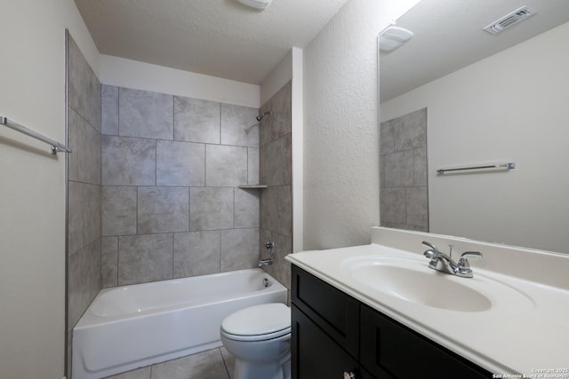 full bathroom with tiled shower / bath, vanity, toilet, tile patterned floors, and a textured ceiling