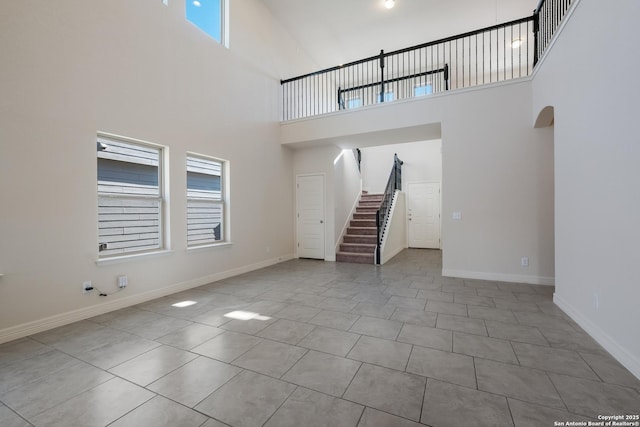 unfurnished living room featuring light tile patterned flooring and a high ceiling