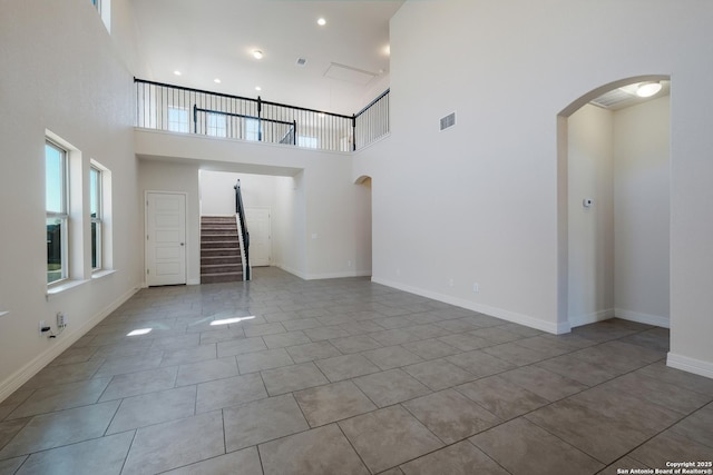 unfurnished living room with tile patterned flooring and a towering ceiling