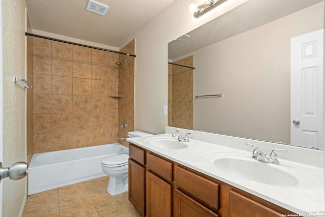 full bathroom with tiled shower / bath combo, vanity, tile patterned flooring, toilet, and a textured ceiling