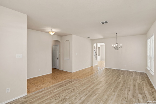 unfurnished room with an inviting chandelier and light hardwood / wood-style floors