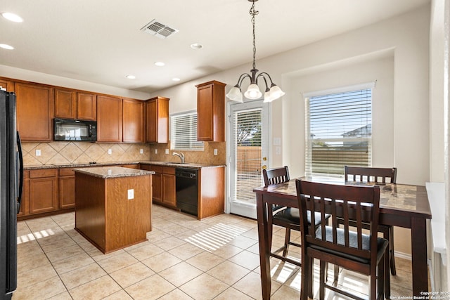 kitchen with pendant lighting, decorative backsplash, a center island, light stone counters, and black appliances