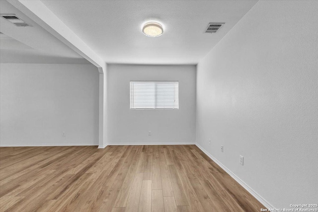 spare room featuring light hardwood / wood-style floors and a textured ceiling