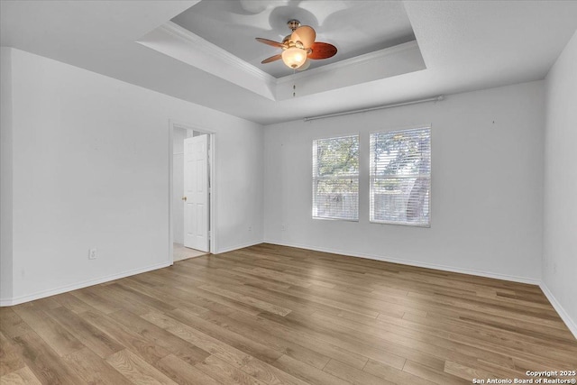 unfurnished room featuring ceiling fan, ornamental molding, a raised ceiling, and light hardwood / wood-style floors