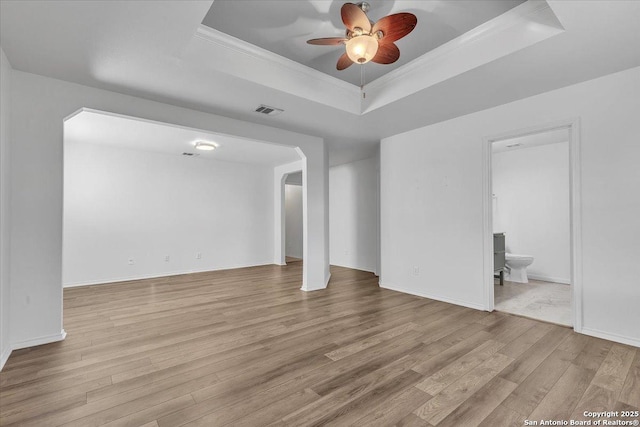 unfurnished living room featuring crown molding, ceiling fan, a raised ceiling, and light hardwood / wood-style floors