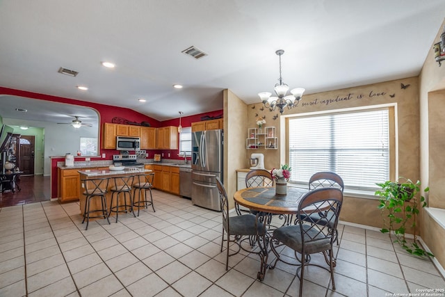 tiled dining space with lofted ceiling, sink, and ceiling fan with notable chandelier