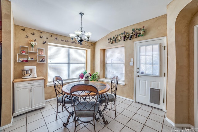 dining area with lofted ceiling, light tile patterned floors, and a notable chandelier