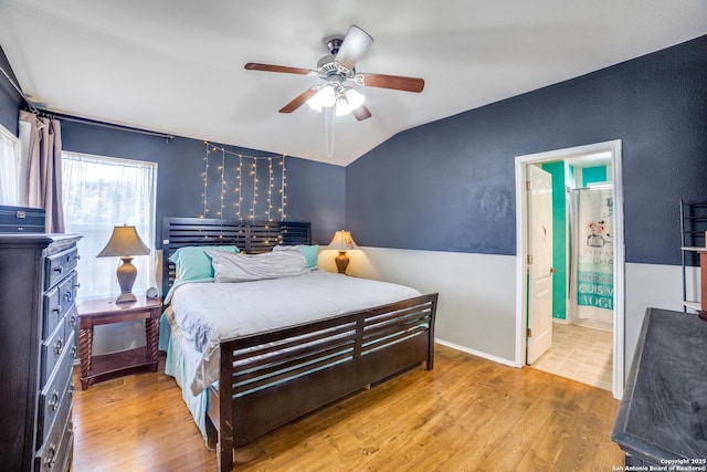 bedroom featuring connected bathroom, vaulted ceiling, ceiling fan, and light wood-type flooring