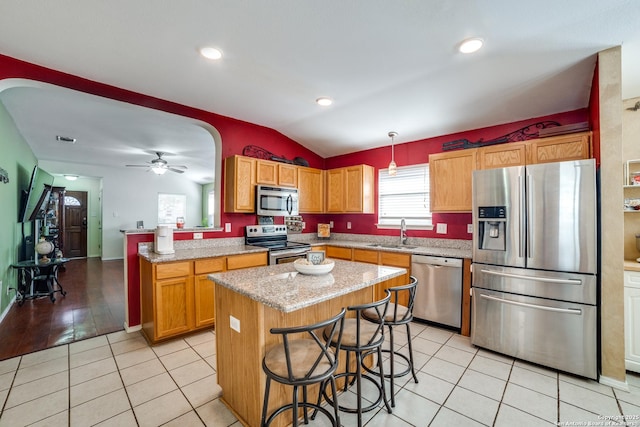 kitchen with lofted ceiling, sink, appliances with stainless steel finishes, hanging light fixtures, and a kitchen island