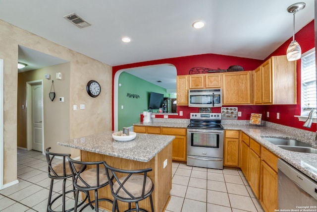 kitchen with sink, a breakfast bar area, vaulted ceiling, appliances with stainless steel finishes, and pendant lighting