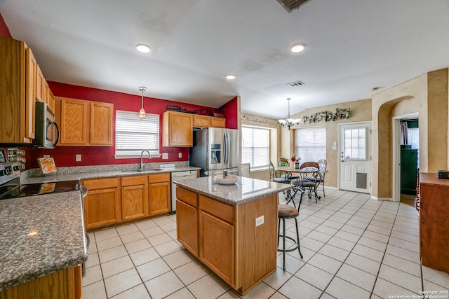 kitchen with a kitchen island, pendant lighting, sink, dark stone counters, and stainless steel appliances