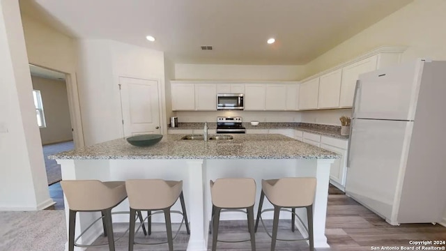 kitchen with white cabinetry, appliances with stainless steel finishes, sink, and an island with sink