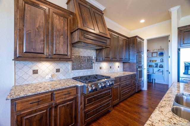 kitchen with appliances with stainless steel finishes, dark hardwood / wood-style flooring, decorative backsplash, ornamental molding, and light stone counters