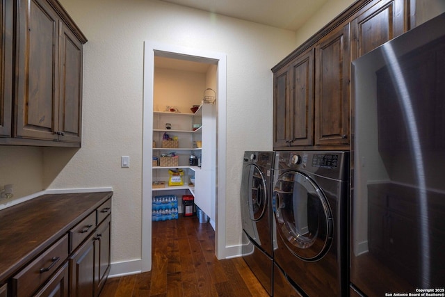 clothes washing area with dark hardwood / wood-style flooring, cabinets, and washing machine and clothes dryer