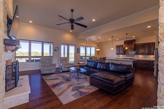 living room featuring dark wood-type flooring, a fireplace, ornamental molding, and ceiling fan