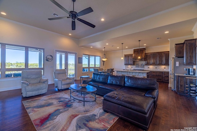 living room featuring dark hardwood / wood-style flooring, sink, crown molding, and ceiling fan