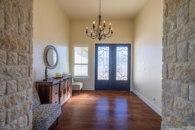 foyer with dark wood-type flooring, a chandelier, and french doors