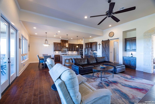 living room featuring dark hardwood / wood-style floors, ornamental molding, and a barn door