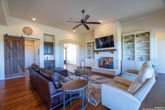 living room with dark hardwood / wood-style flooring, a fireplace, built in features, and a barn door