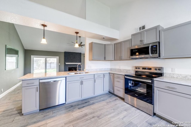 kitchen featuring sink, ceiling fan, appliances with stainless steel finishes, hanging light fixtures, and kitchen peninsula