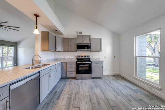 kitchen with pendant lighting, sink, gray cabinets, appliances with stainless steel finishes, and light wood-type flooring