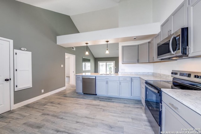 kitchen featuring high vaulted ceiling, decorative light fixtures, sink, light hardwood / wood-style floors, and stainless steel appliances