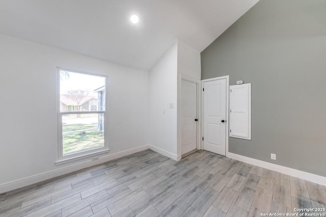 spare room with high vaulted ceiling and light hardwood / wood-style floors