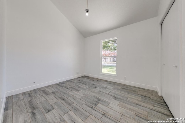 spare room featuring lofted ceiling and light hardwood / wood-style floors