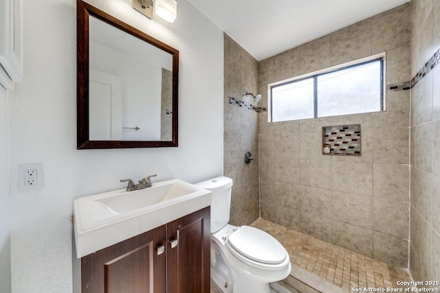 bathroom with vanity, toilet, and tiled shower