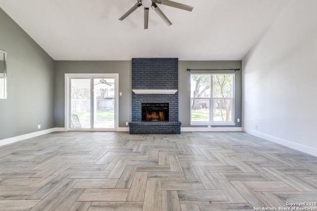 unfurnished living room with ceiling fan, light parquet flooring, and a brick fireplace