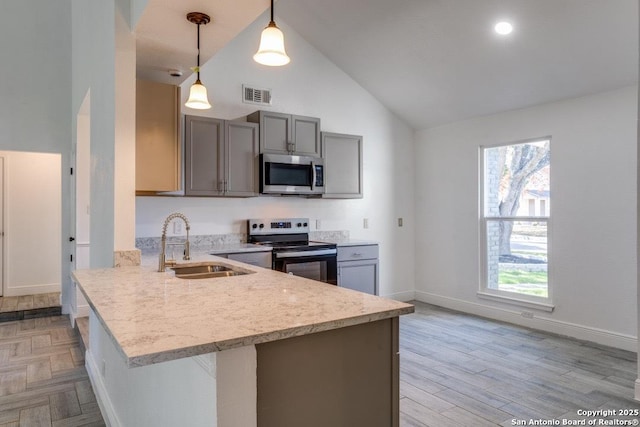 kitchen with stainless steel appliances, hanging light fixtures, gray cabinetry, and kitchen peninsula