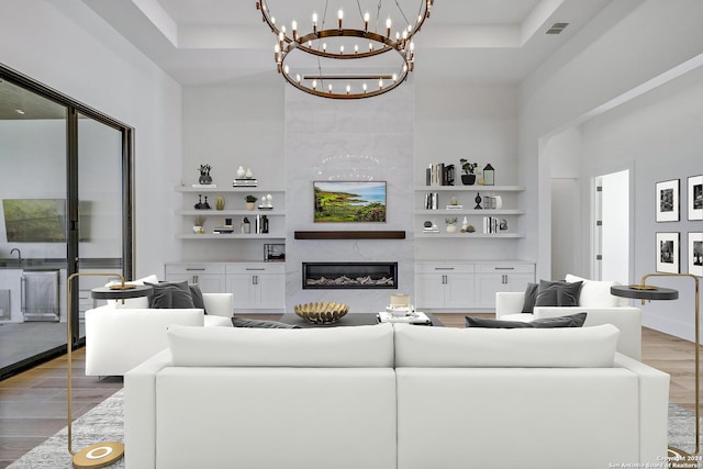 living room featuring light hardwood / wood-style flooring, built in features, a premium fireplace, and a high ceiling