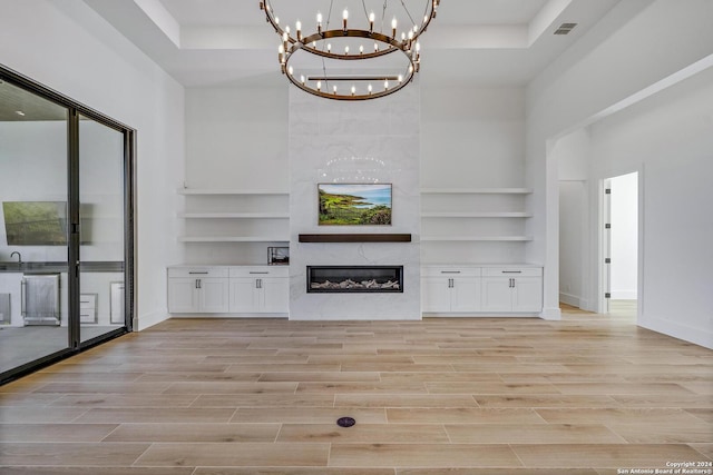 unfurnished living room featuring a towering ceiling, a high end fireplace, and a tray ceiling