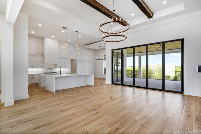 unfurnished living room with sink, beam ceiling, and a high ceiling