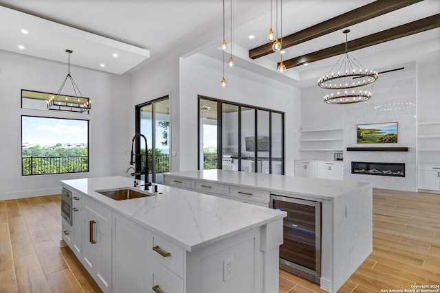 kitchen featuring beverage cooler, decorative light fixtures, sink, and a large island with sink