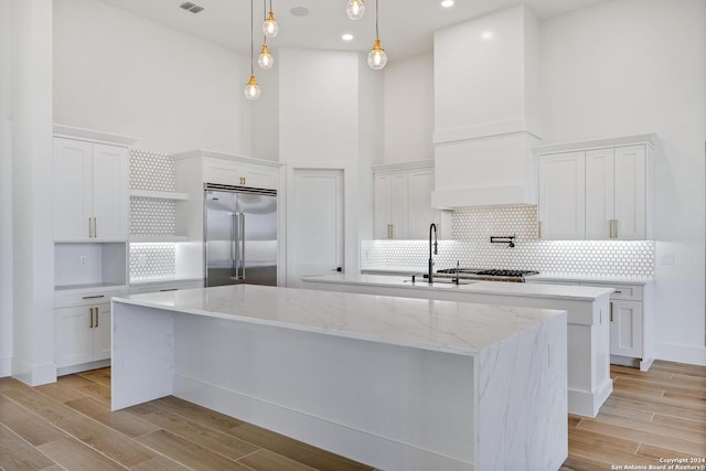 kitchen featuring stainless steel built in refrigerator, a center island, and white cabinets