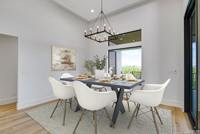 dining space with a towering ceiling and light hardwood / wood-style flooring