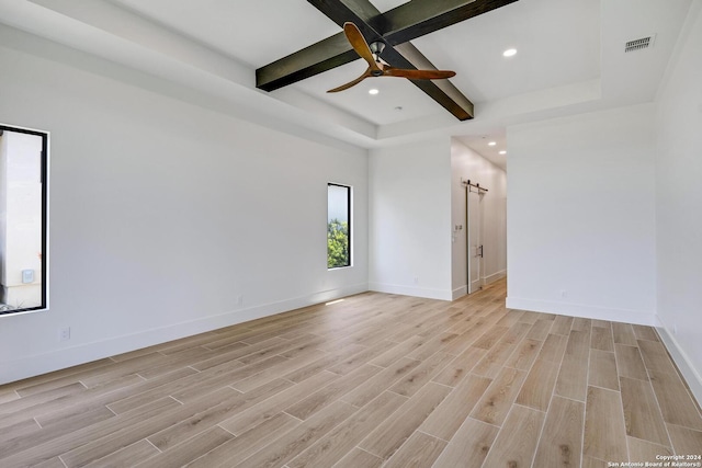 unfurnished room featuring beamed ceiling, a barn door, ceiling fan, and light hardwood / wood-style flooring