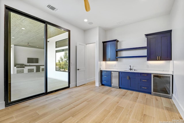 kitchen with wine cooler, blue cabinetry, decorative backsplash, and light wood-type flooring