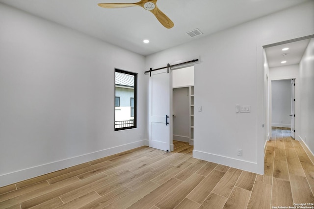 empty room with a barn door and ceiling fan