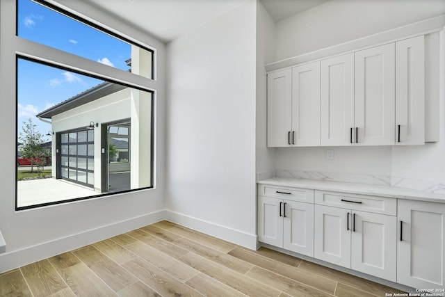 interior space with light stone countertops, light hardwood / wood-style floors, and white cabinets