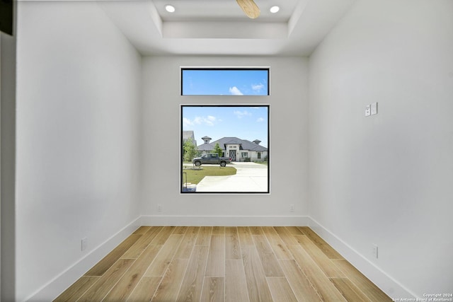 spare room featuring a raised ceiling and light hardwood / wood-style floors