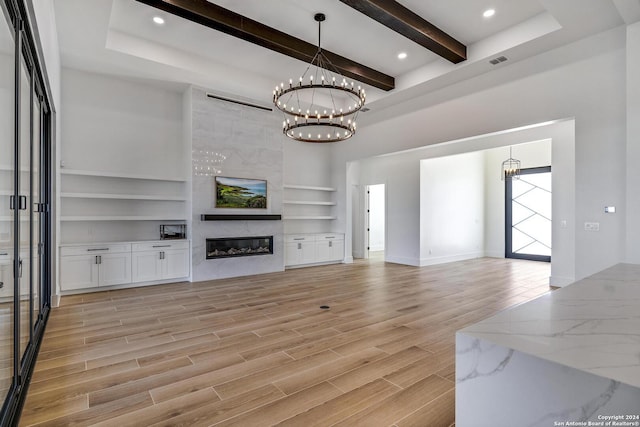 living room with beamed ceiling, a notable chandelier, a fireplace, and built in shelves