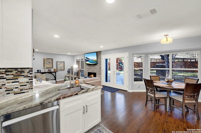 kitchen with dark hardwood / wood-style floors, a fireplace, white cabinetry, decorative backsplash, and light stone countertops