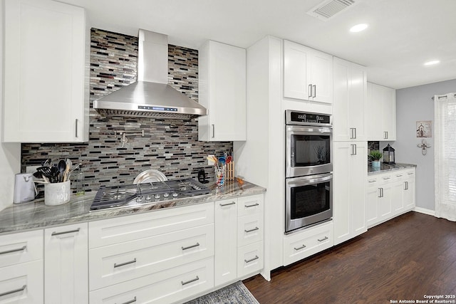 kitchen with stainless steel appliances, white cabinetry, wall chimney range hood, and decorative backsplash