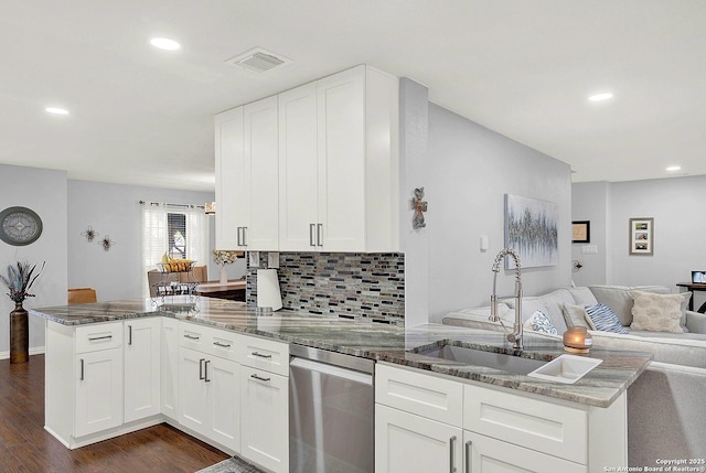 kitchen featuring sink, white cabinetry, kitchen peninsula, dark stone counters, and backsplash